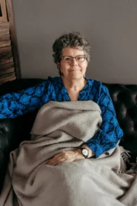 Kimberly sitting on couch covered with blanket